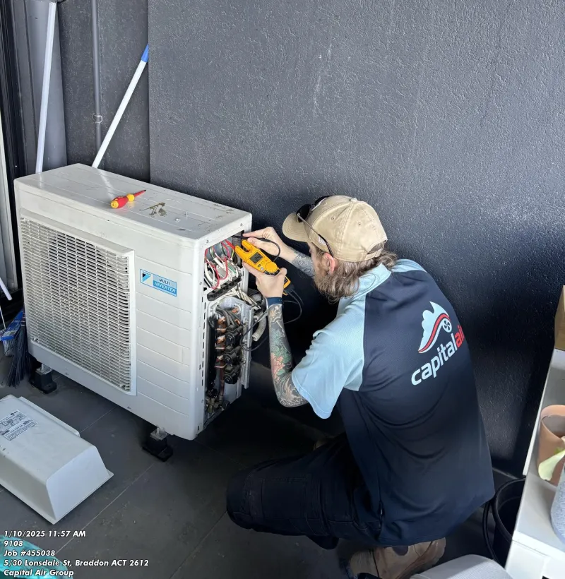 Technician servicing an outdoor air conditioning unit with tools.
