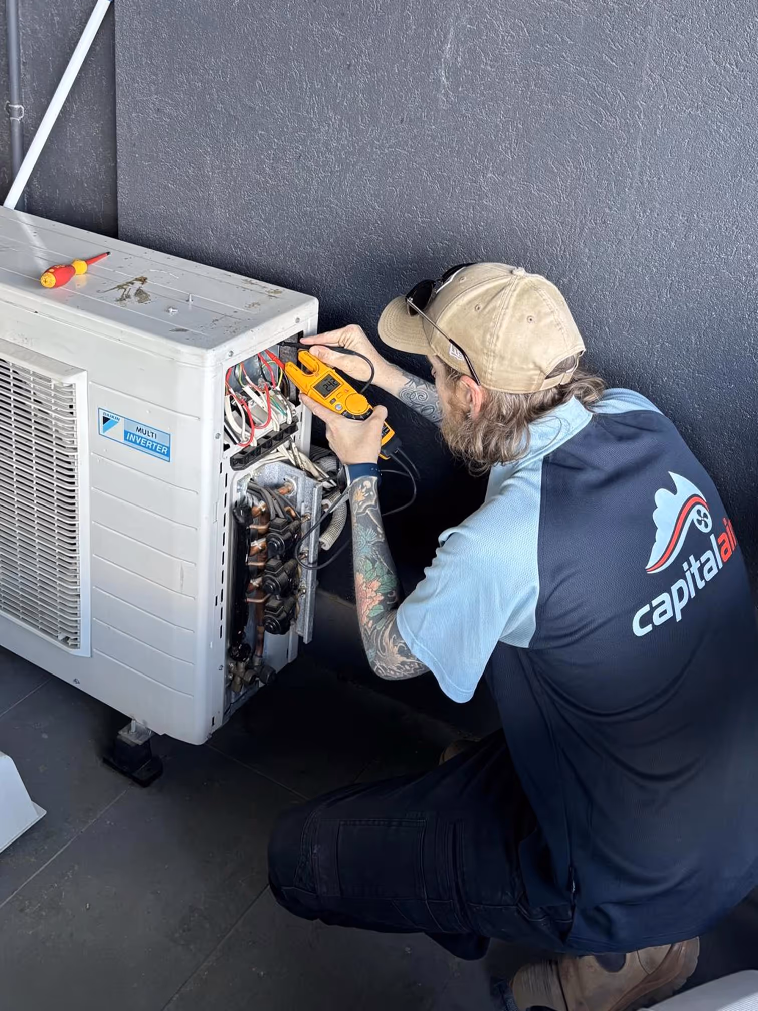 Technician repairing outdoor air conditioning unit in Bungendore home.