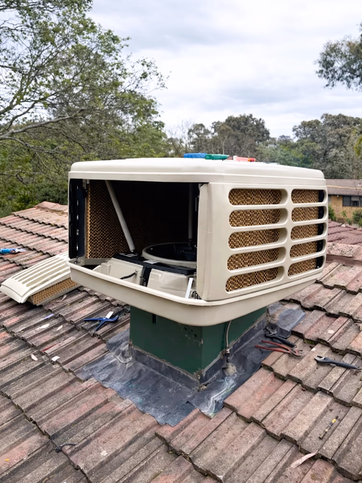 Evaporative air conditioning unit being serviced on a tiled roof in Canberra.
