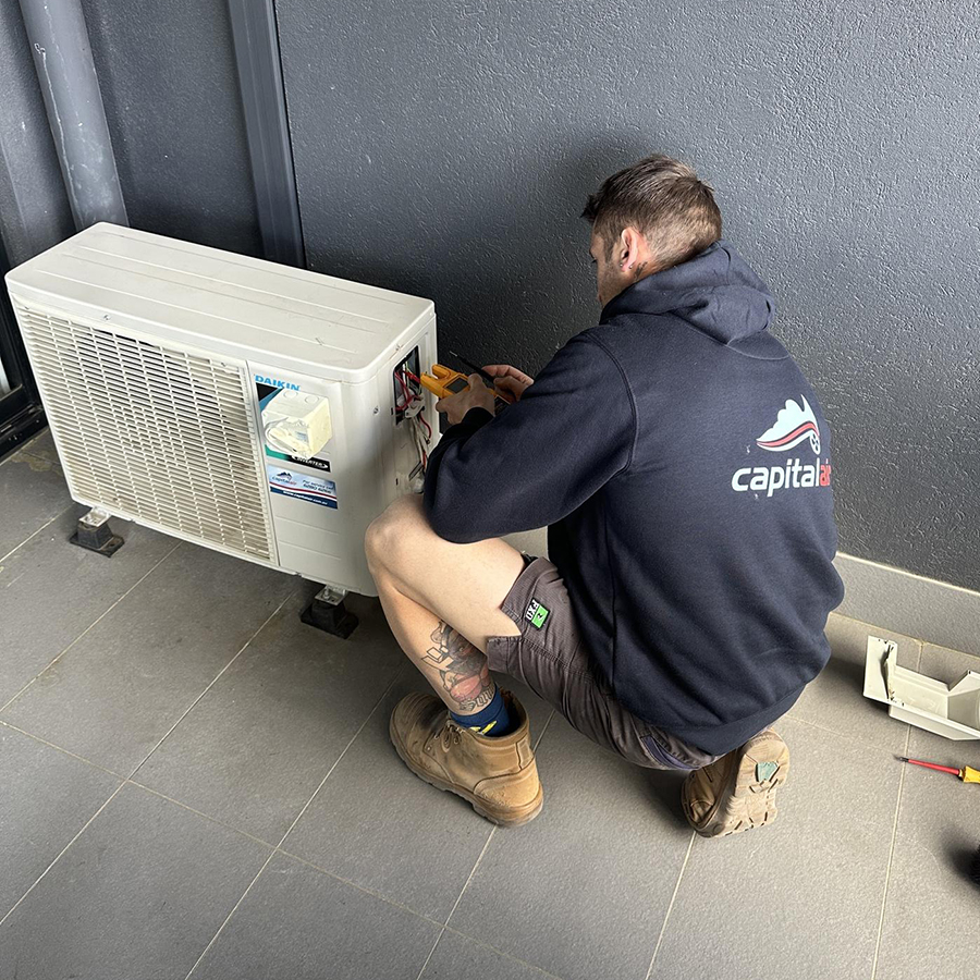 Capital Air technician servicing an external air conditioning system.
