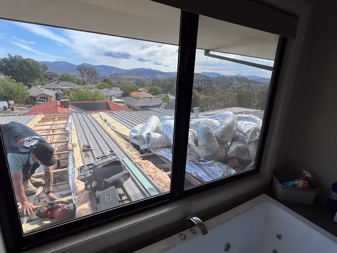 Air conditioning installation taking place on a rooftop with ducting visible.