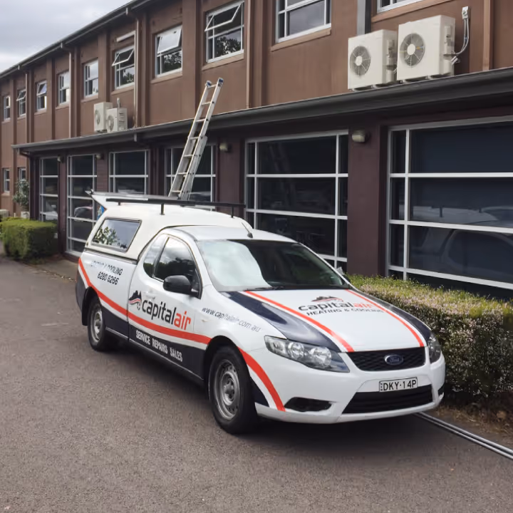 Capital Air service vehicle parked outside a commercial building with multiple air conditioning units.