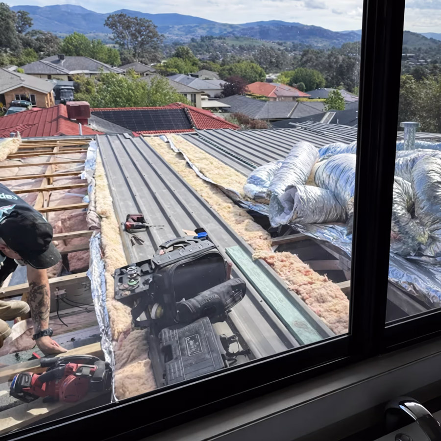 Technician working on ducted air conditioning installation on a residential roof in Canberra.