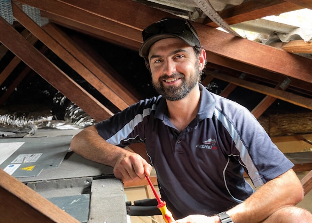 Capital Air technician performing maintenance in ceiling cavity.