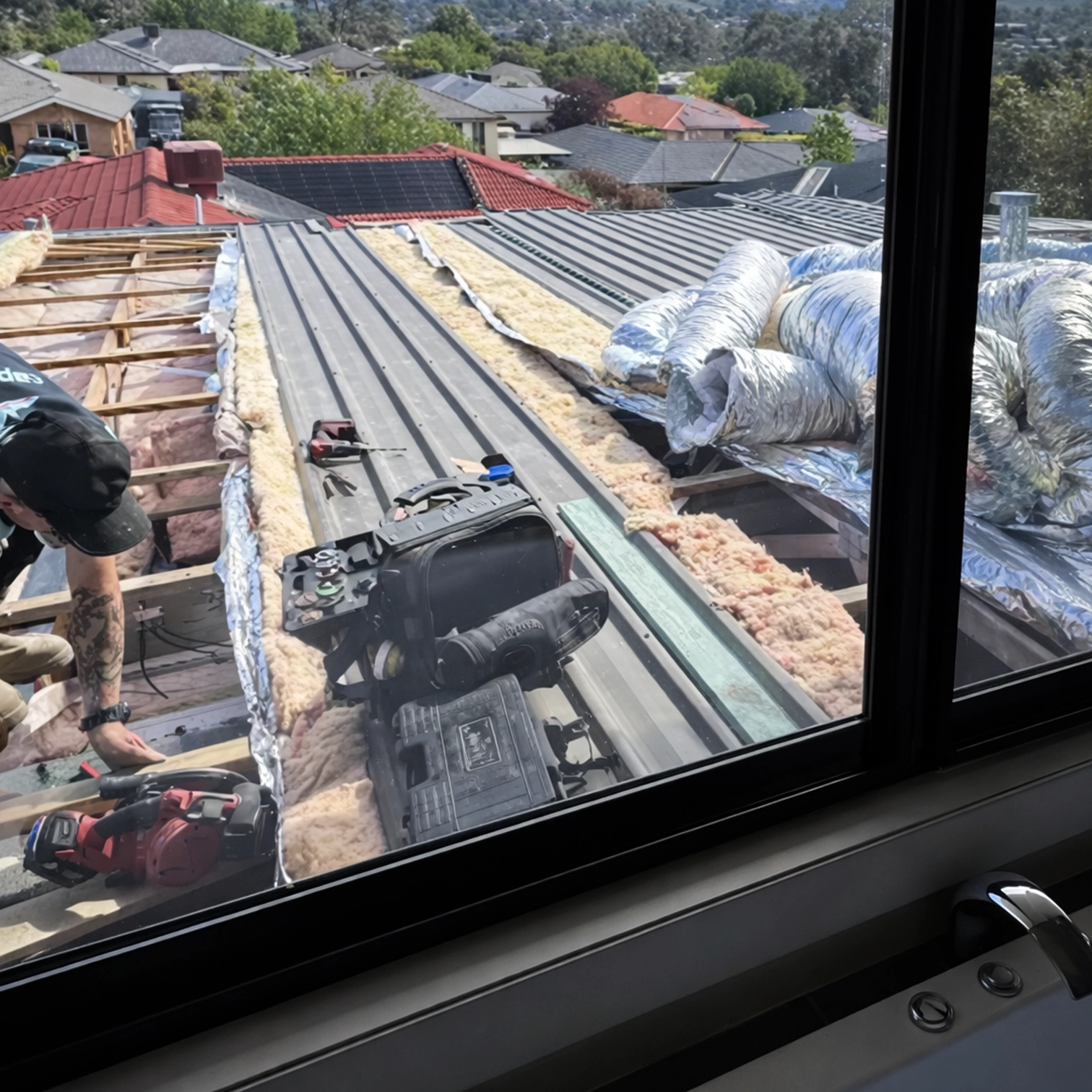 Ducted air conditioning installation across rooftop with insulation and ductwork visible.