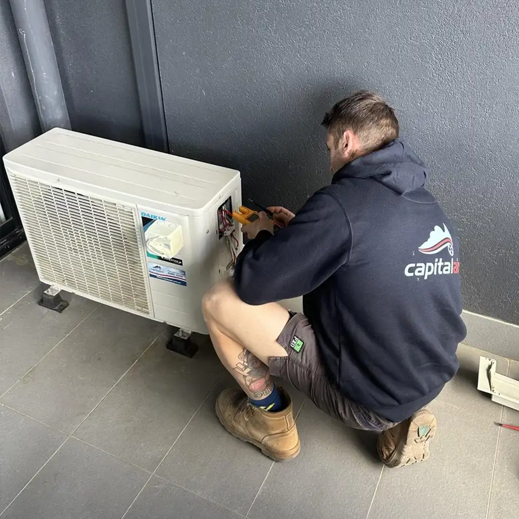 Technician repairing an outdoor air conditioning unit during a service visit in inner-north Canberra.
