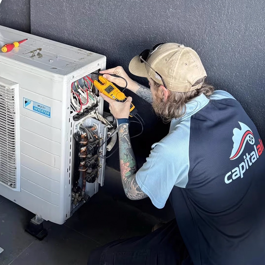 Technician testing and repairing an outdoor air conditioning unit during maintenance.