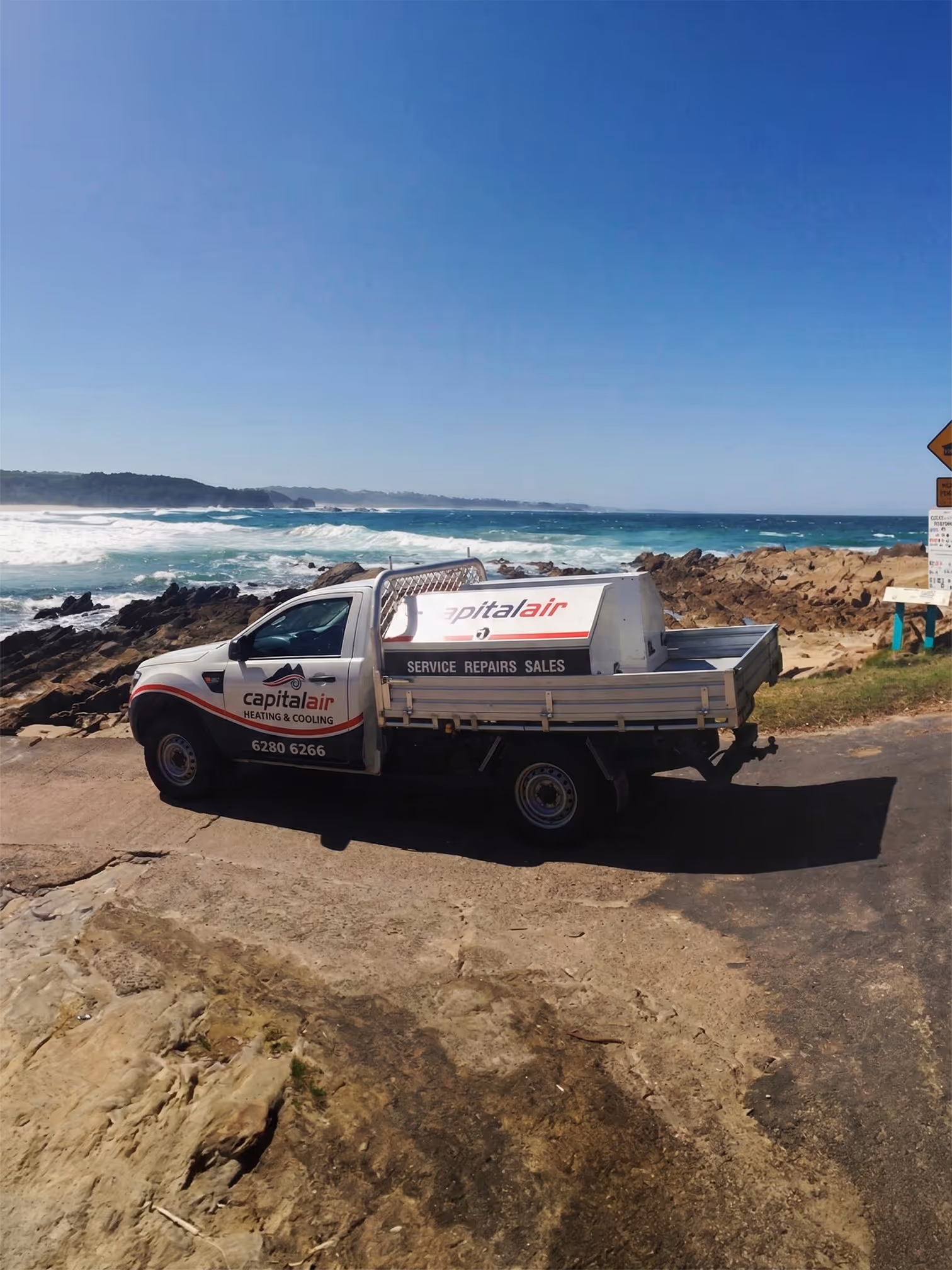 Capital Air service ute parked near the coastline during a job.
