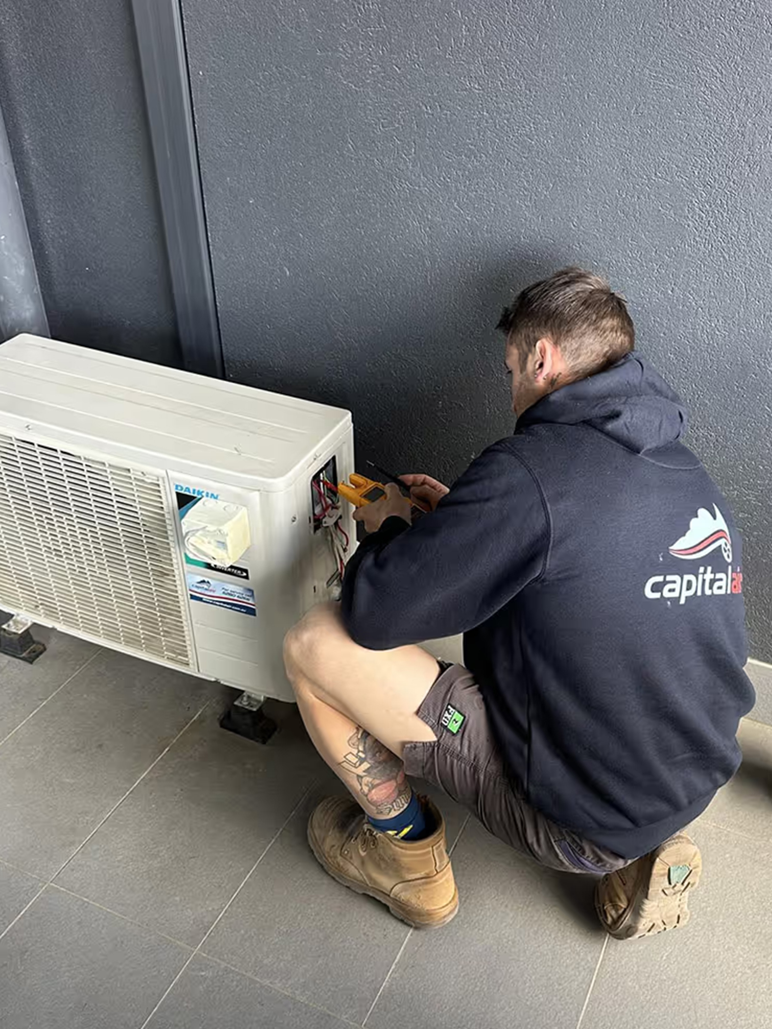 Capital Air technician servicing a Daikin outdoor air conditioning unit.