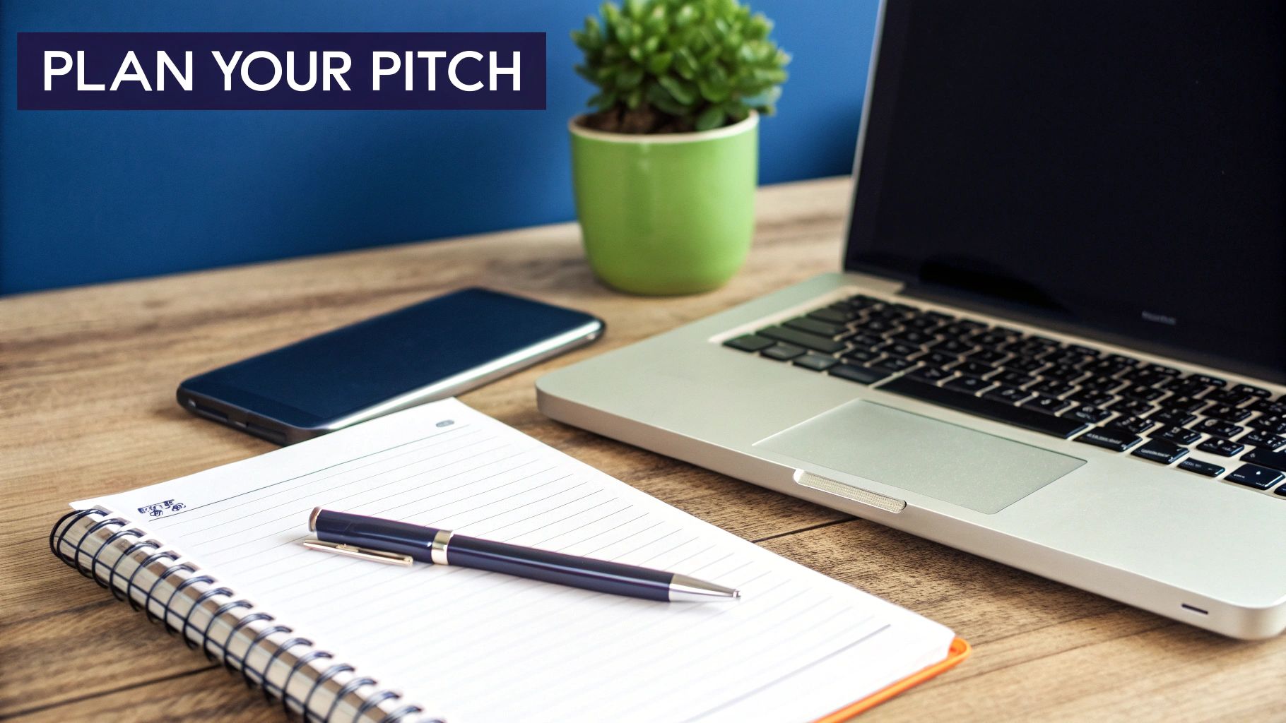 Office desk setup with a laptop, phone, notebook, and pen, featuring a 'PLAN YOUR PITCH' banner.