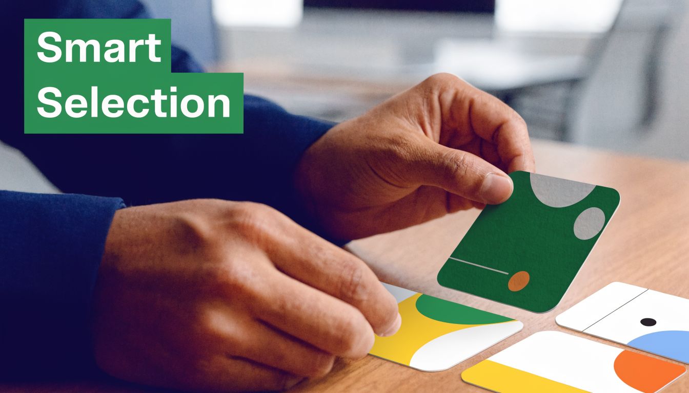 A professional's hands carefully arranging colorful abstract design cards on a wooden office desk.