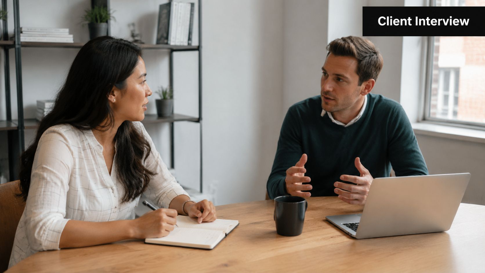 A professional man and woman discussing business strategies together at a wooden table during an interview.