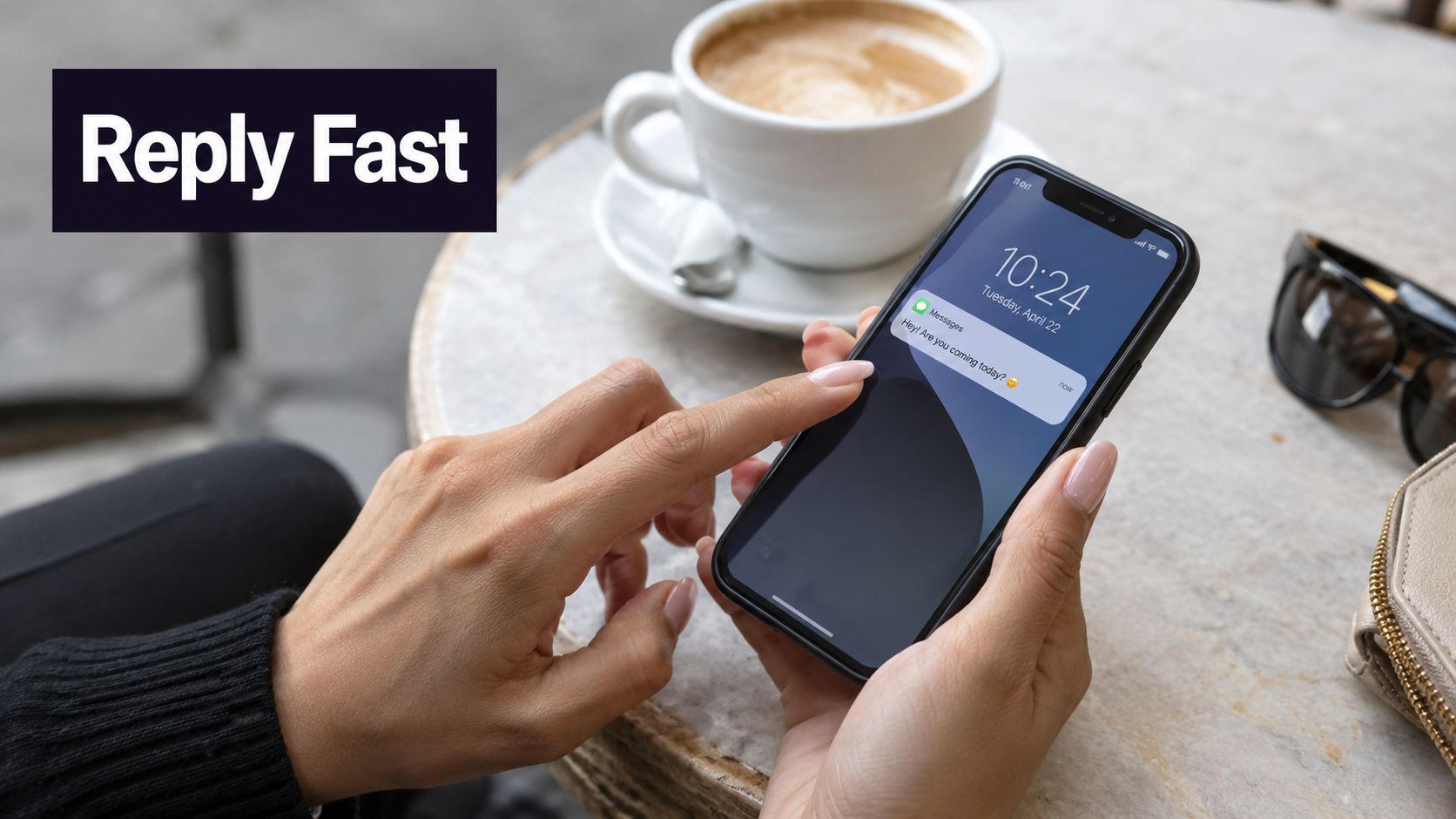 A person holding a smartphone showing a text notification while sitting at a cafe table.