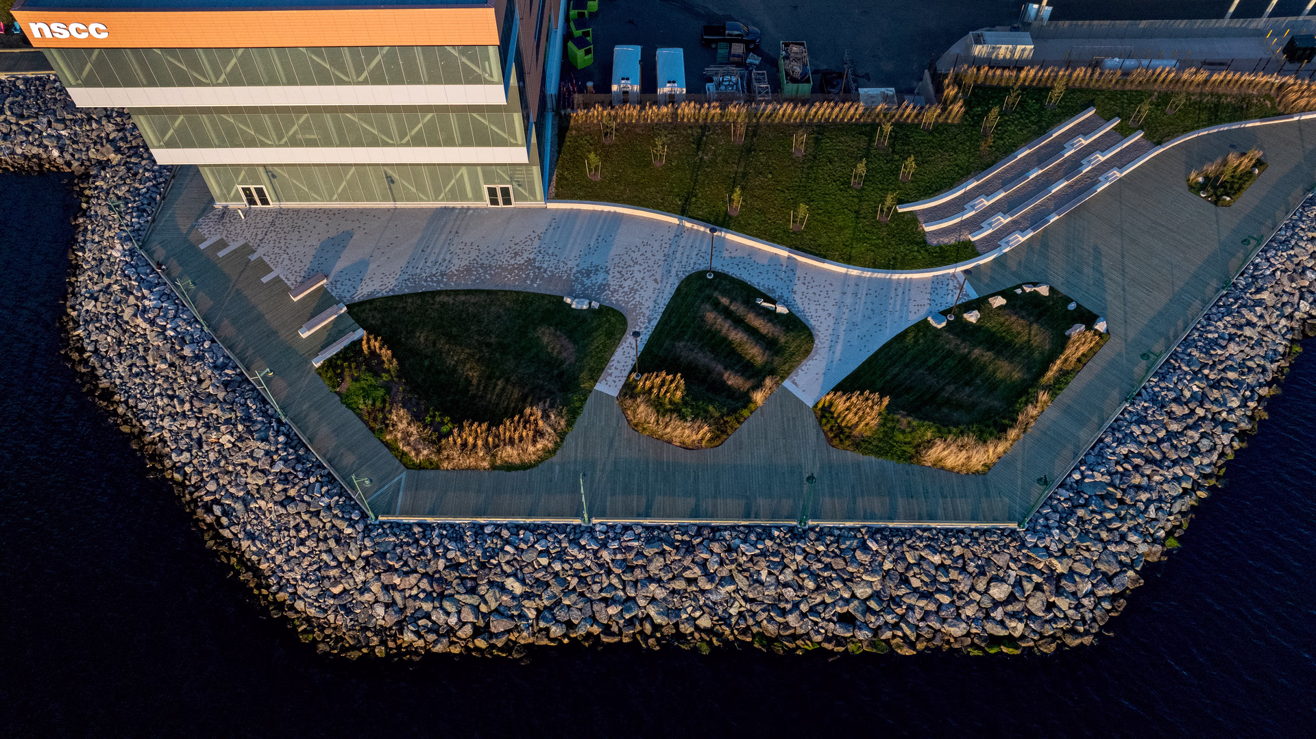 Aerial view of NSCC waterfront building with adjacent landscaped grassy areas, boardwalk, and rocky shoreline.