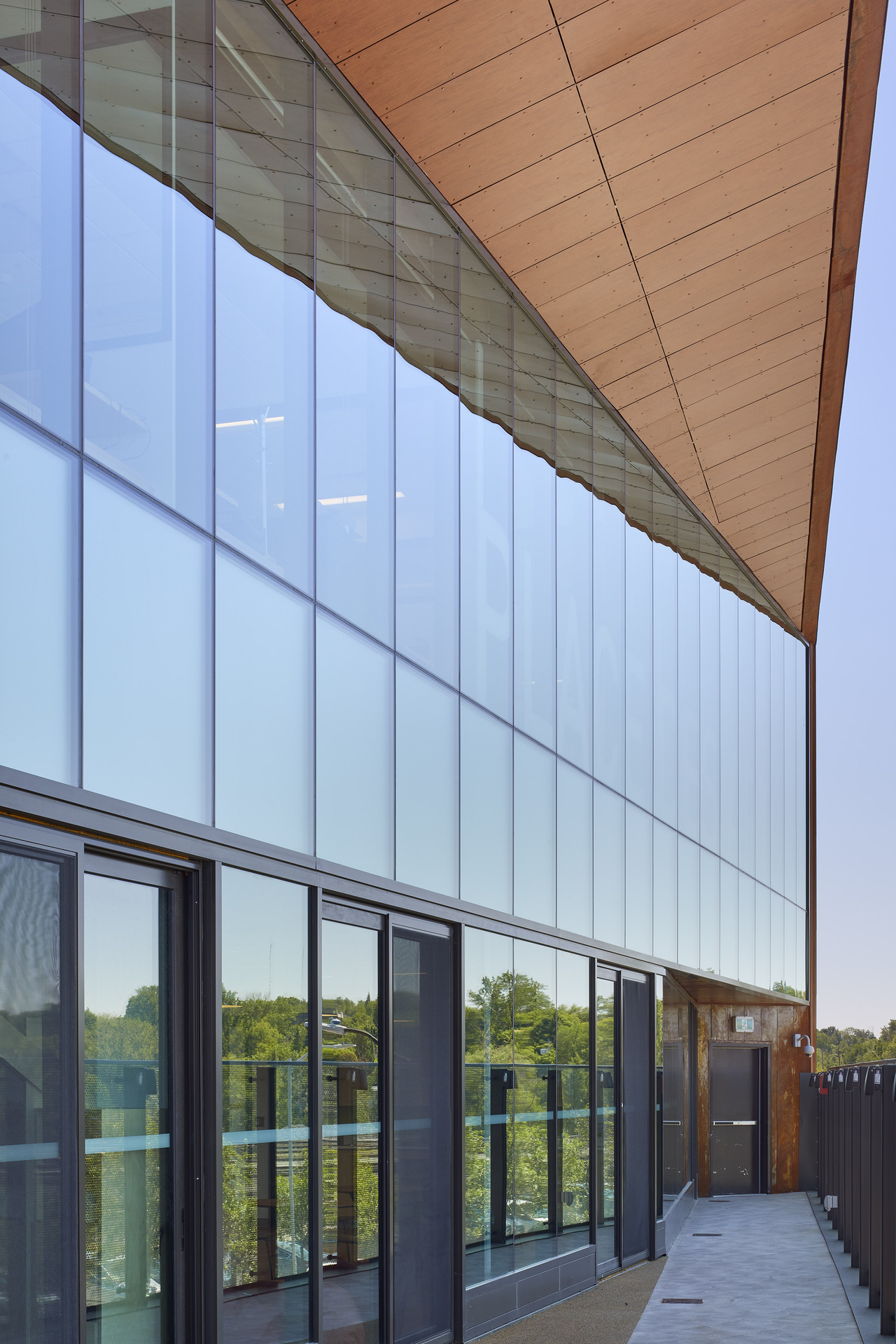 Modern building exterior with large reflective glass panels and brown angled roof overhang.