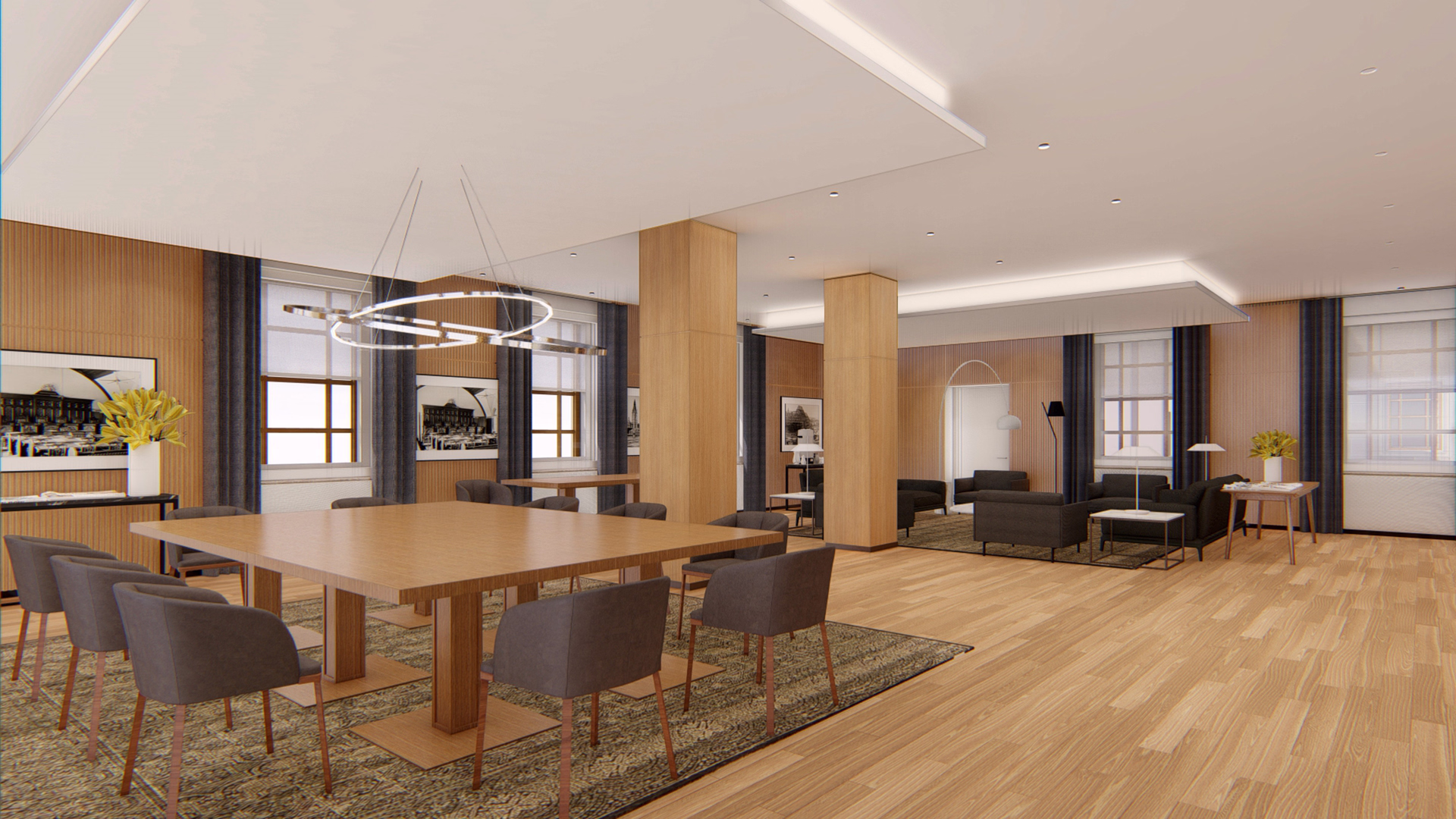 Modern office lounge with a large wooden table surrounded by dark gray chairs on a patterned rug and a seating area with black sofas and armchairs.