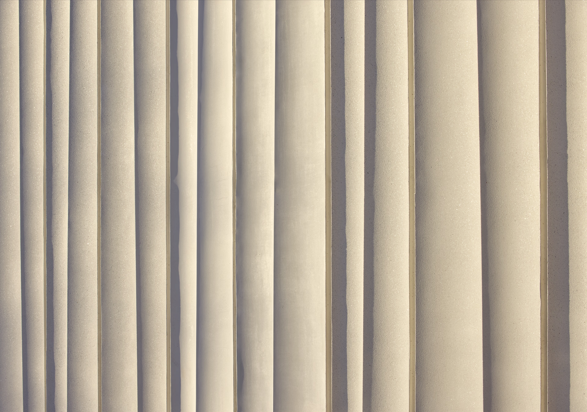 Close-up of vertical beige architectural columns with shadows.