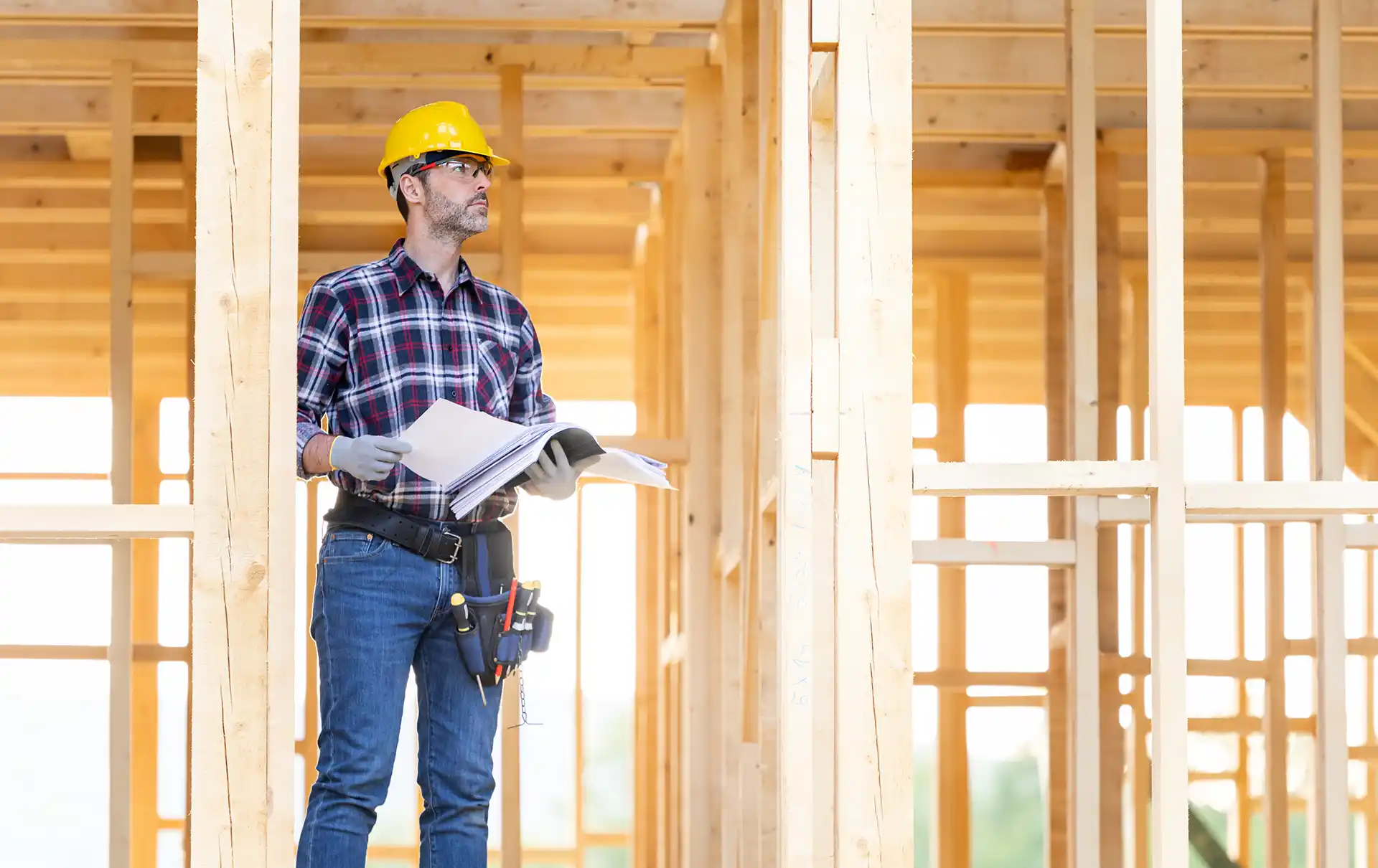 Framing contractor standing inside home with frames around him.
