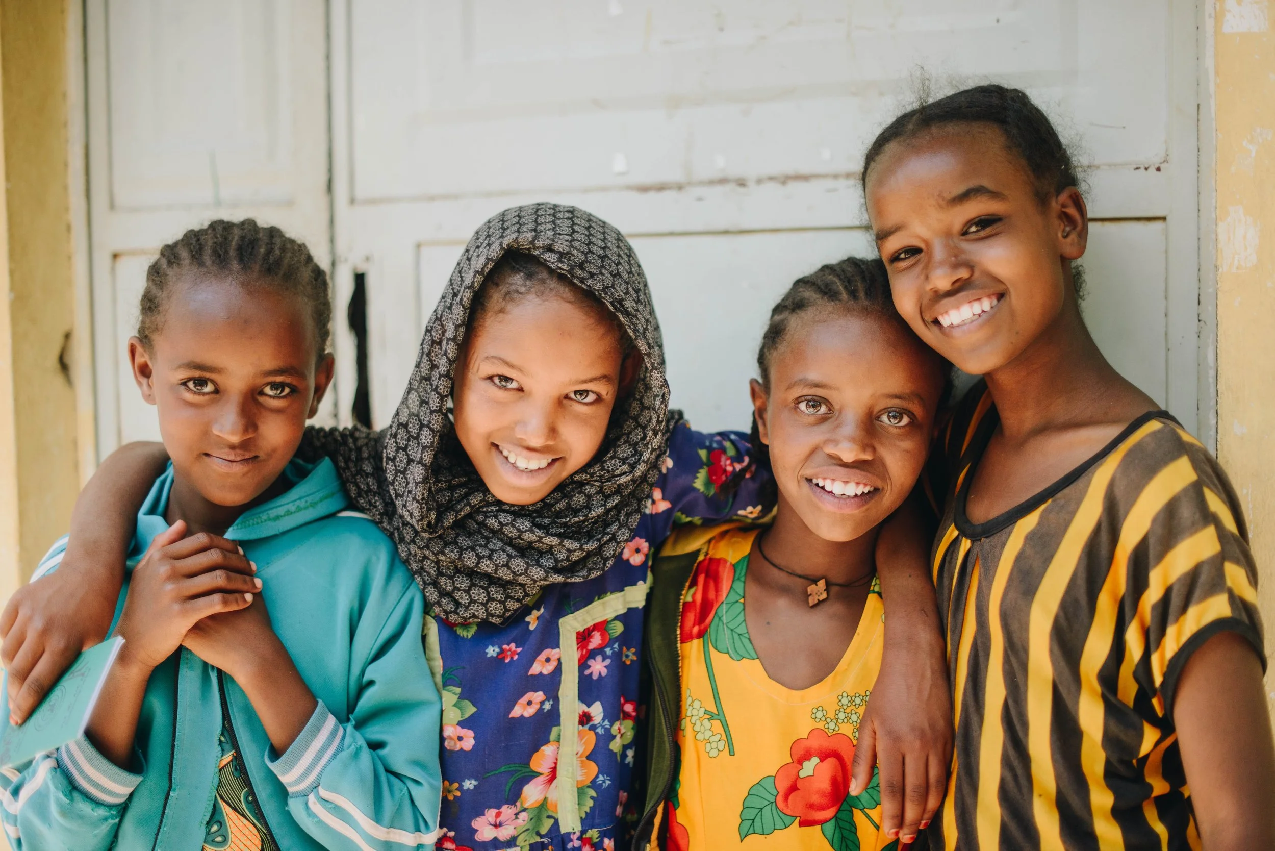 4 children stand close and smile at the camera
