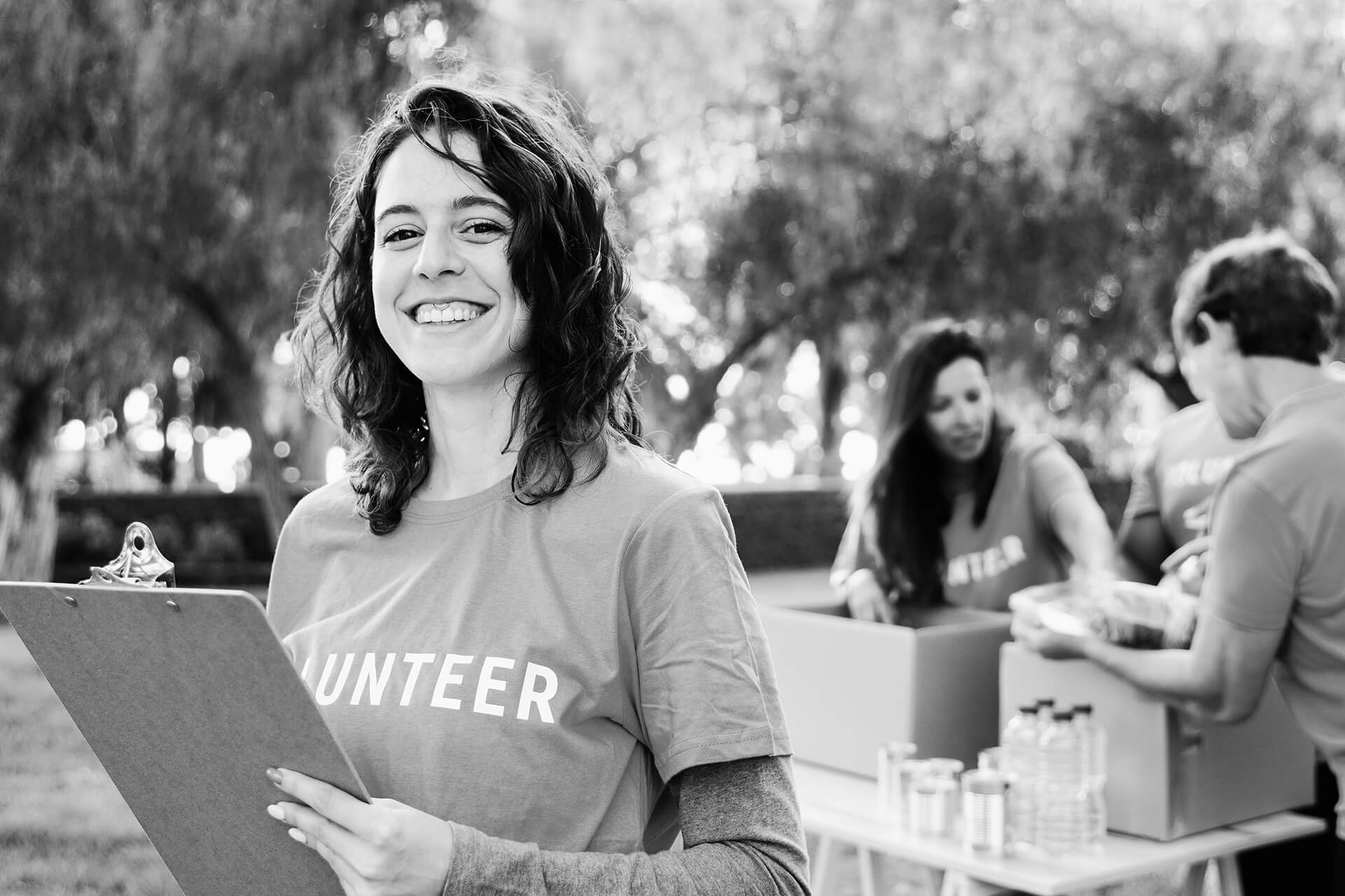 A volunteer coordinator stands with a clipboard smiling at the camera.