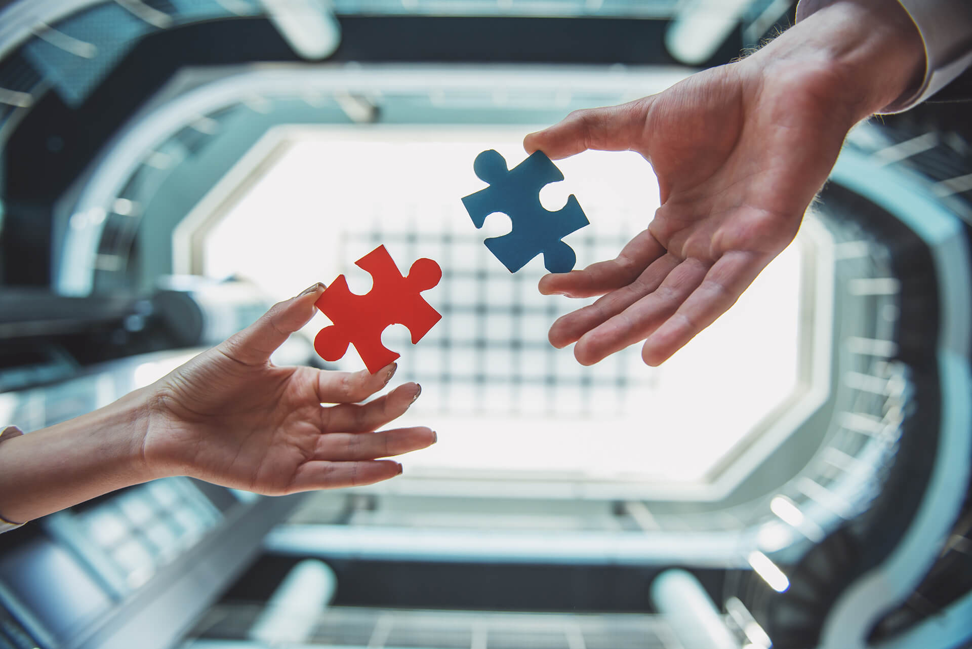 Two hands each hold a puzzle piece that was designed to connect to one another.