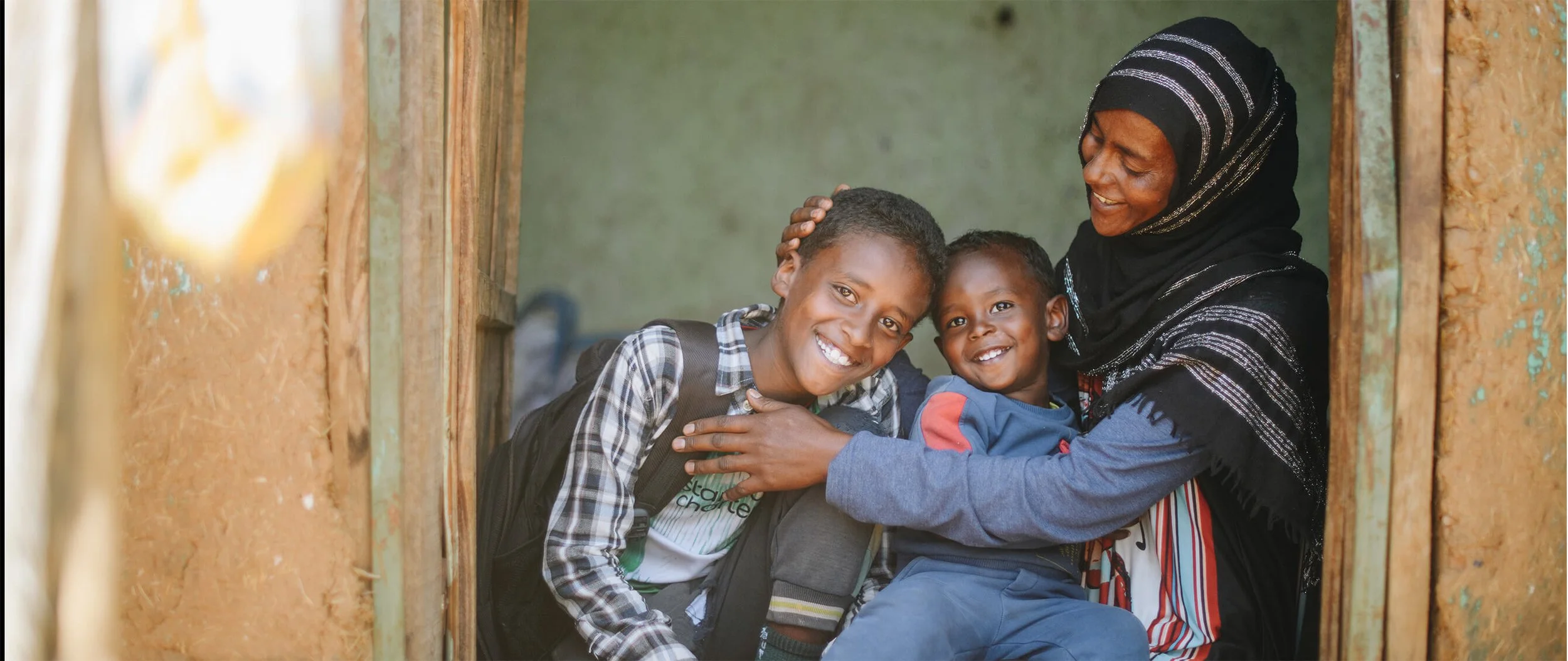 A woman embraces two young children
