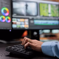 Main d'une personne tapant sur un clavier avec un écran d'ordinateur flou en arrière-plan.
