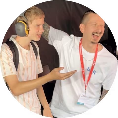 Deux hommes souriants, l'un avec des protections auditives et un sac à dos, discutant joyeusement.