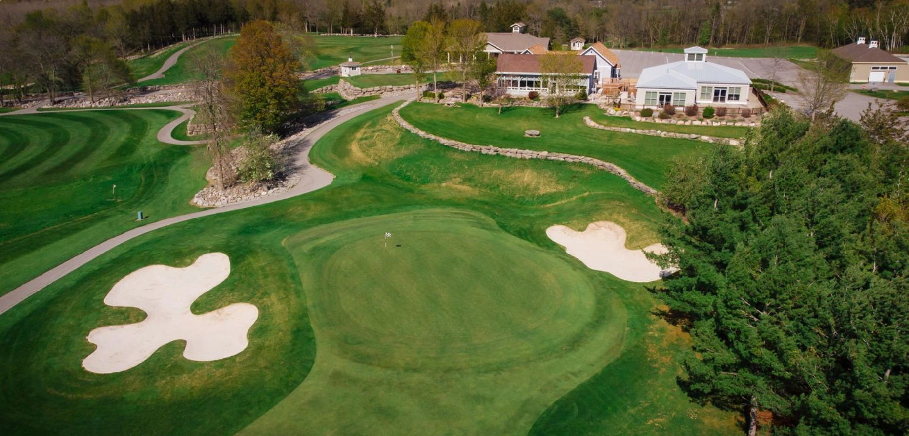 Aerial view of Black Bear Ridge golf course, sand bunker, surrounding trees, and fairway under natural sunlight.