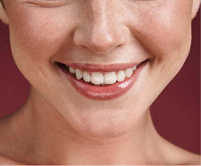 Close-up of a smiling person’s mouth showing white teeth and glossy lips.