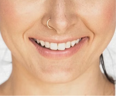 Close-up of a smiling person with a nose ring and white teeth.