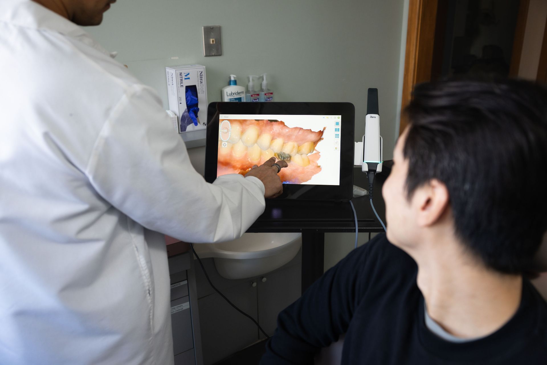 Dentist showing a digital 3D image of a patient's teeth on a screen during a consultation.
