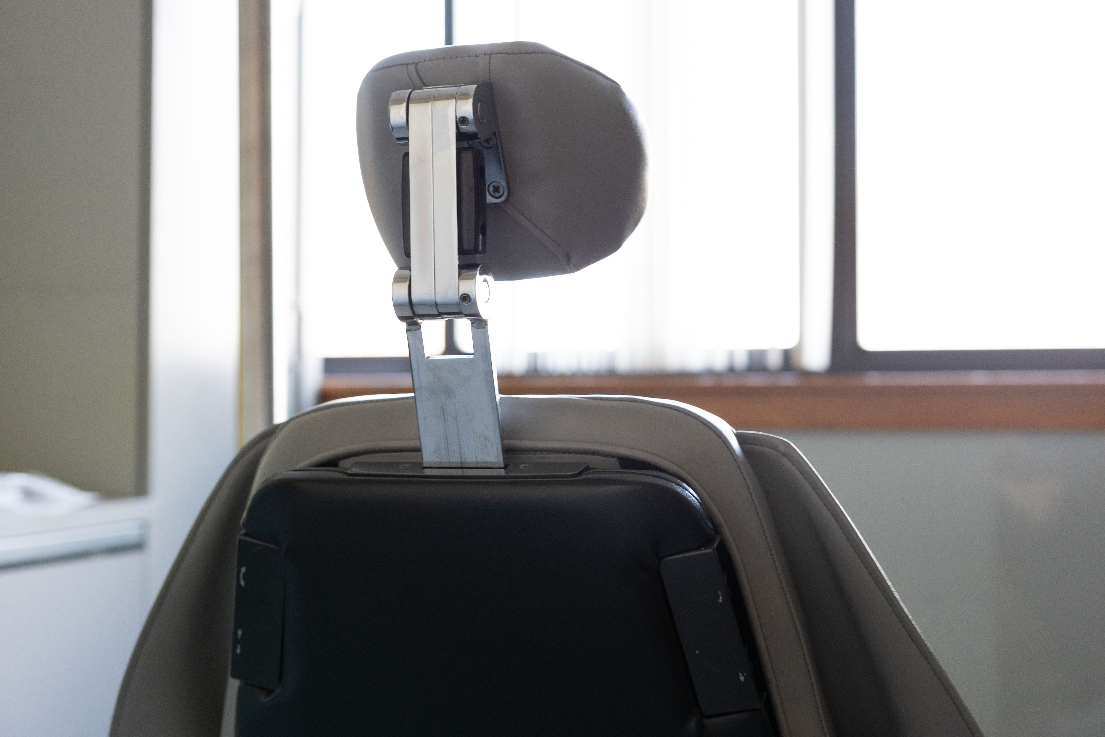 Rear view of a gray and black office chair with an adjustable headrest in front of a window.