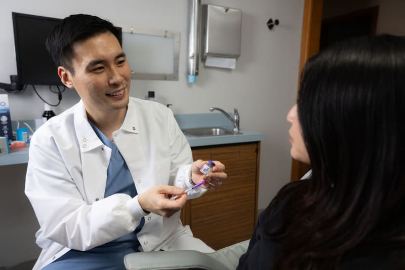 Male dentist showing dental implant model to female patient in clinical setting