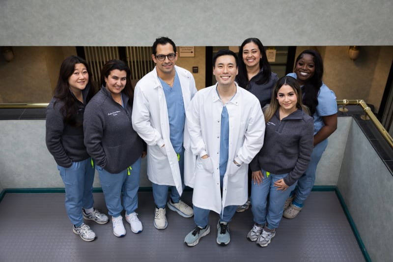 Dental team of diverse professionals in white coats standing together in clinical setting