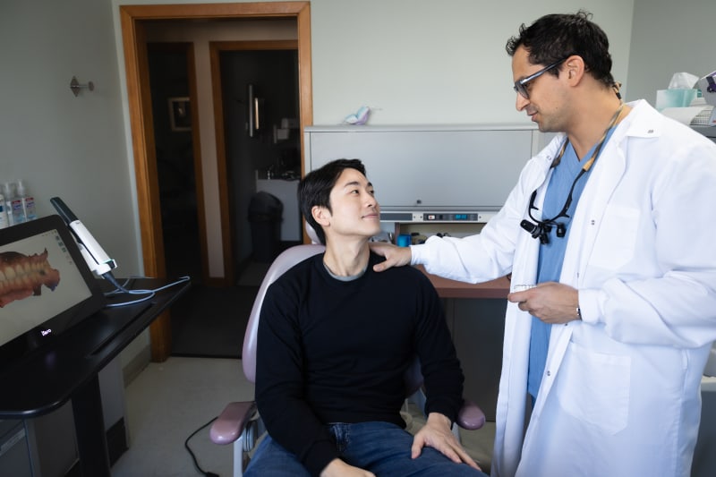 Dentist performing examination on patient in dental operatory with equipment visible