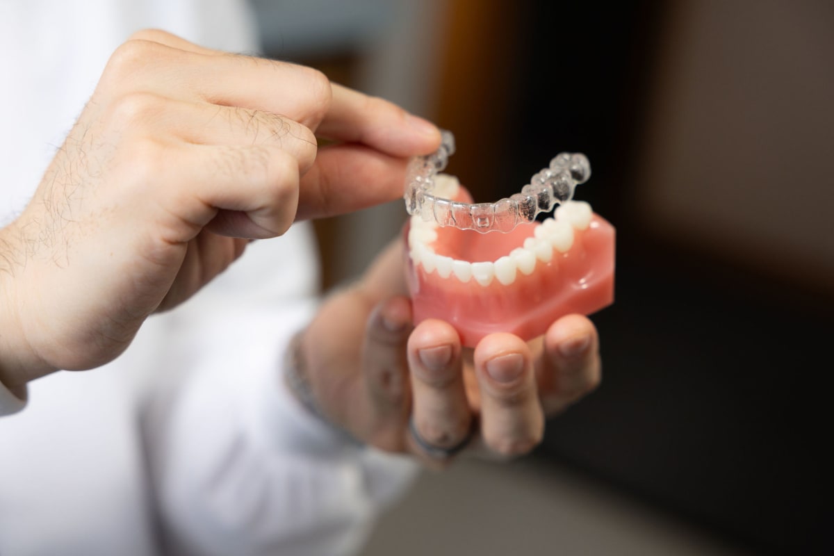 Dentist holding clear aligner model demonstrating Invisalign treatment to patient