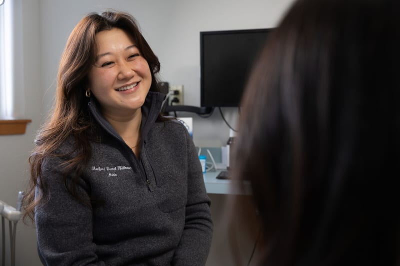 Female dental professional smiling during patient consultation in treatment room