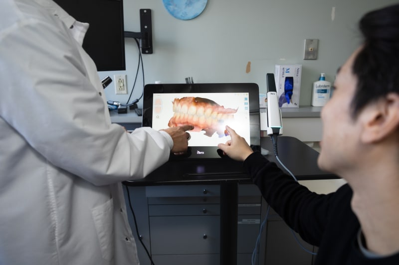 Dentist showing digital scan on tablet screen during patient consultation