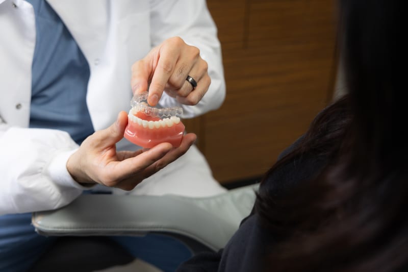 Dentist demonstrating dental model showing tooth structure and alignment to patient
