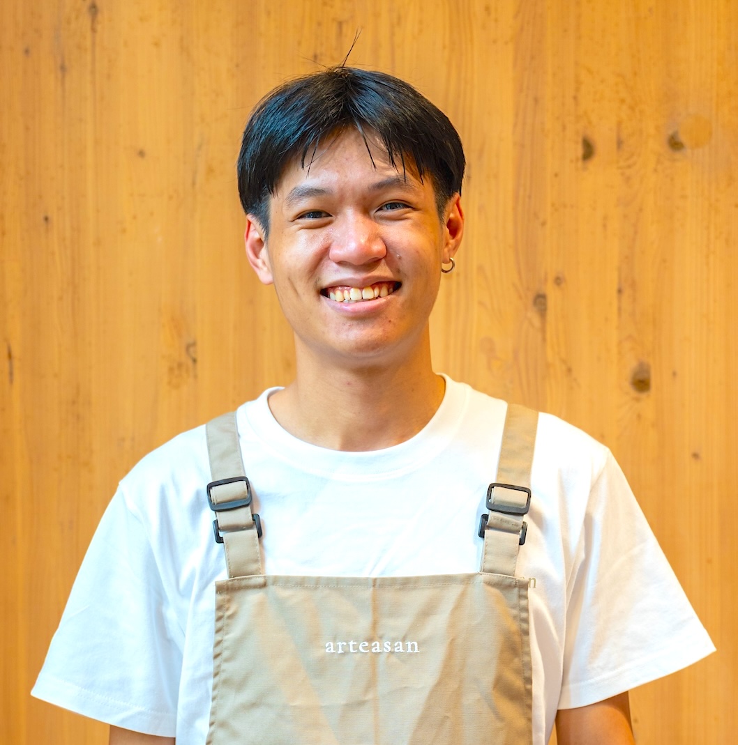 An Arteasan team member smiling against a wooden backdrop