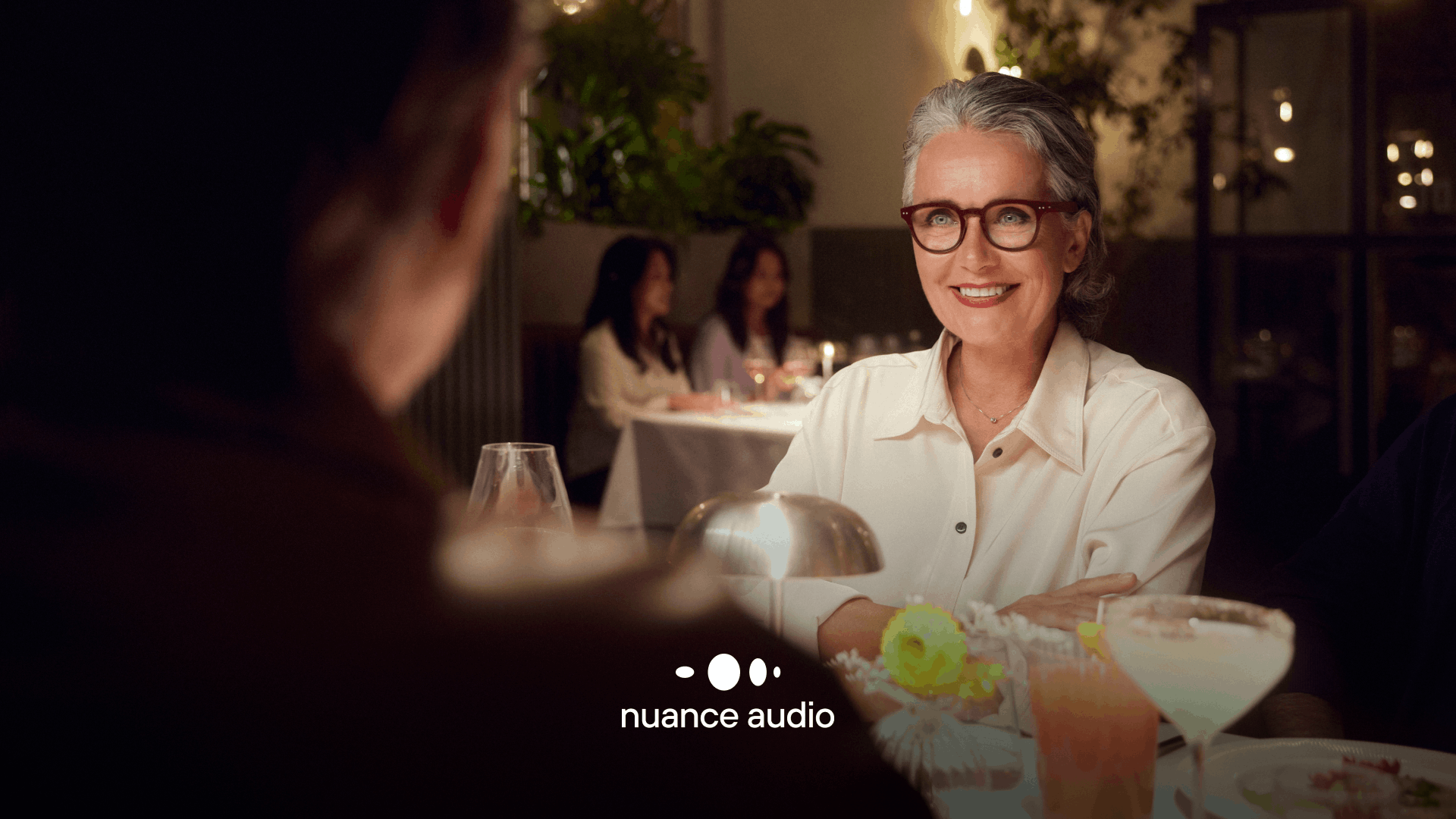 Woman wearing Nuance Audio Glasses at a dinner table