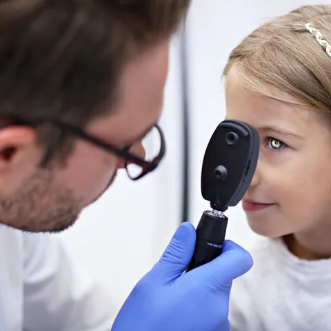 Child undergoing a comprehensive eye test with an optometrist in a clinical setting