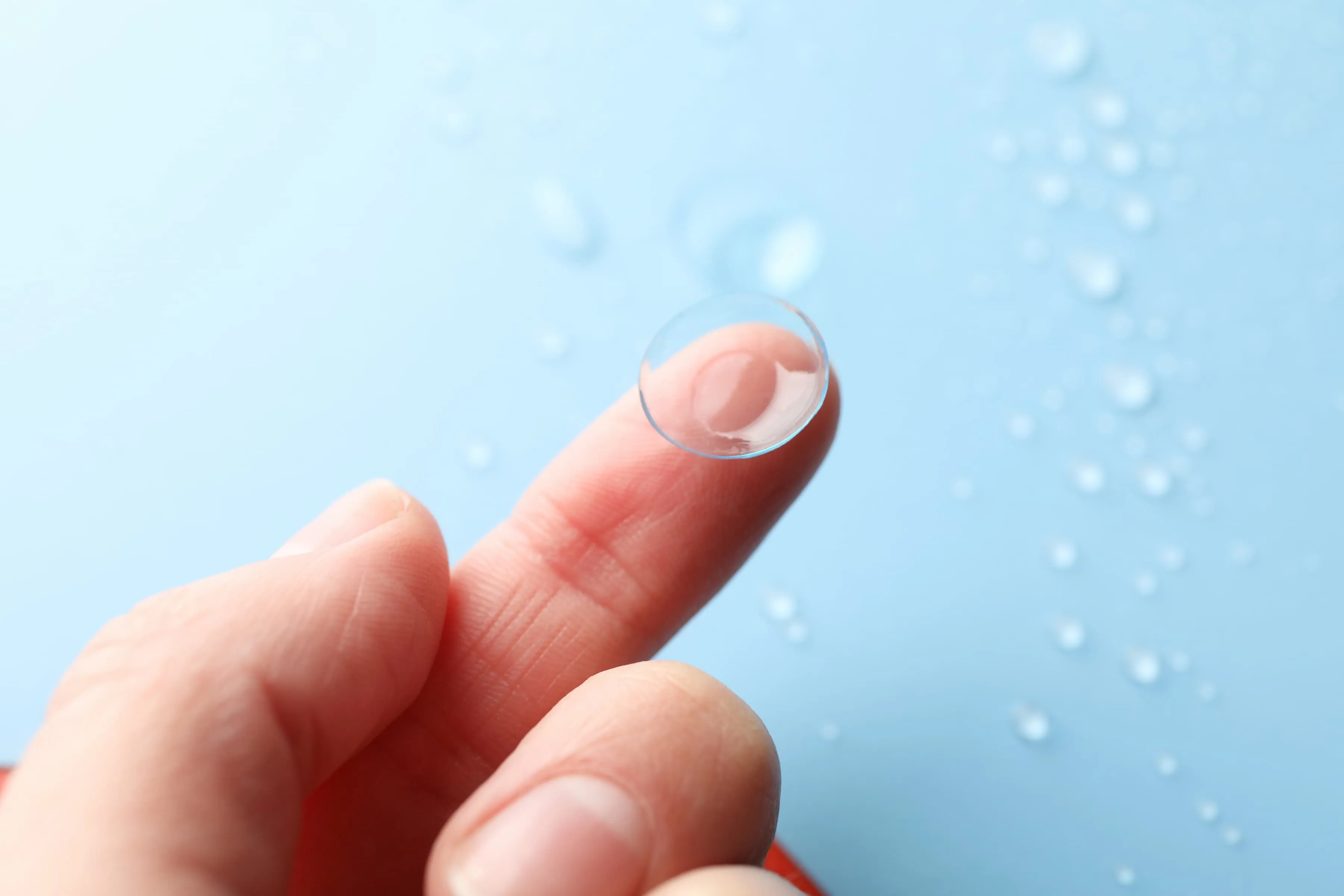 Contact lens on fingertip showing proper handling before insertion for vision correction
