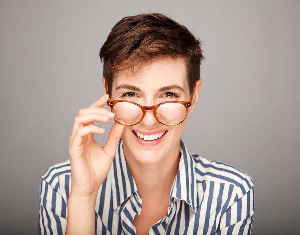 Smiling woman wearing stylish designer eyeglasses, showcasing modern prescription frames