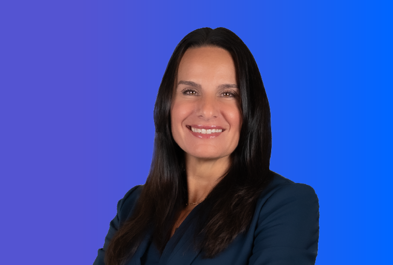 Smiling woman with long dark hair wearing a dark blazer against a blue gradient background.