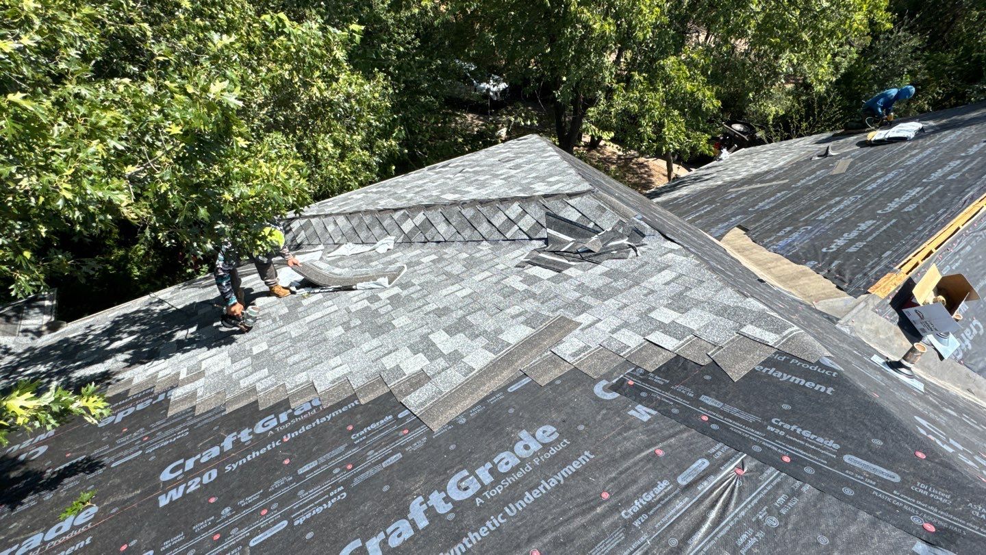Crew installing architectural shingles over synthetic underlayment