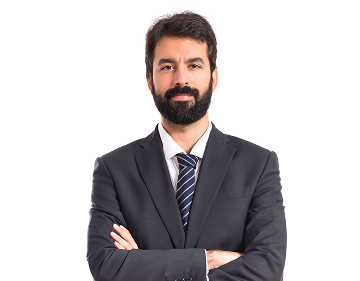 Bearded man in a black suit with a striped tie, standing with arms crossed and smiling slightly.
