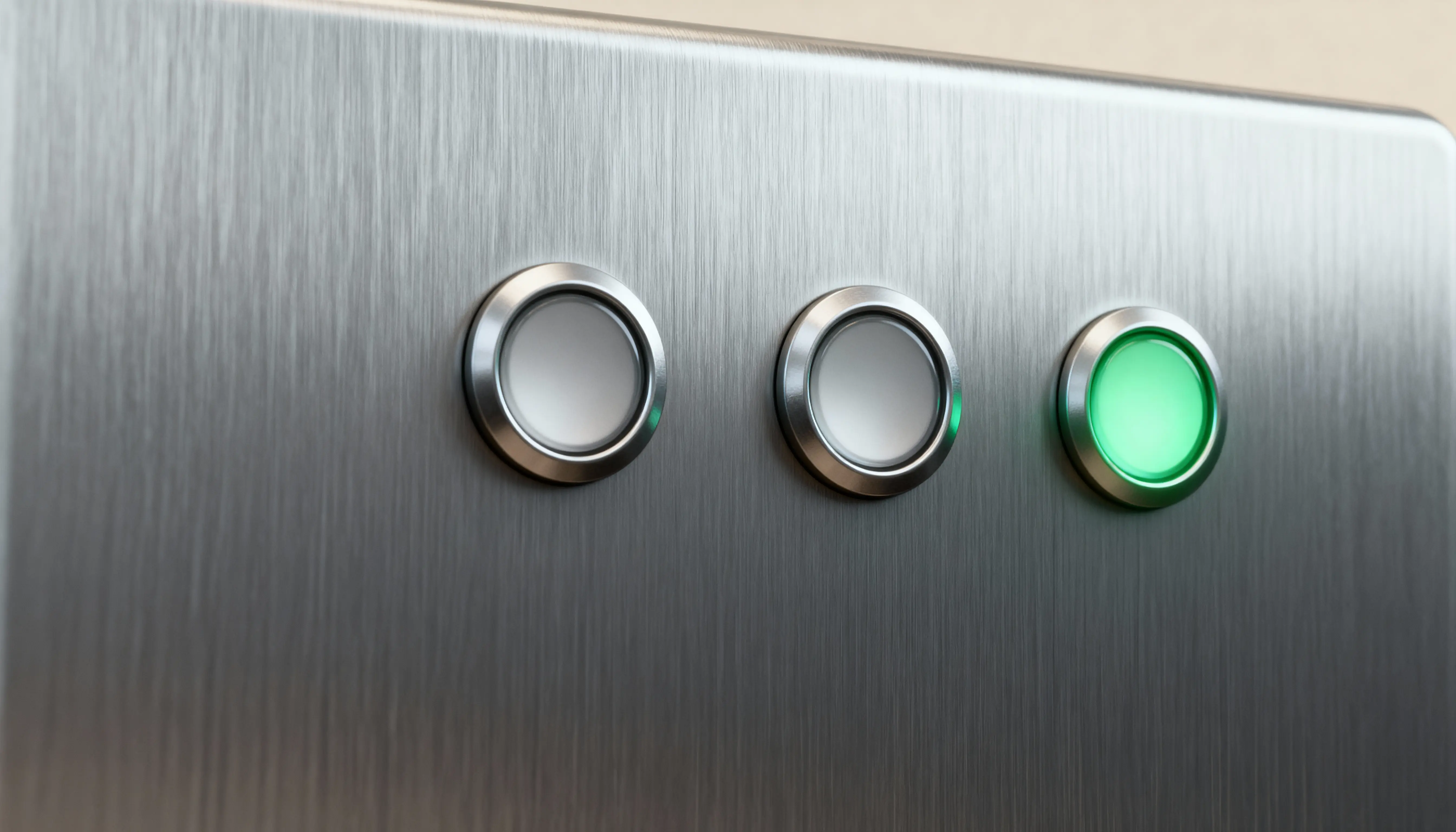 Tre metallknappar på en panel, där den högra knappen lyser i grönt.