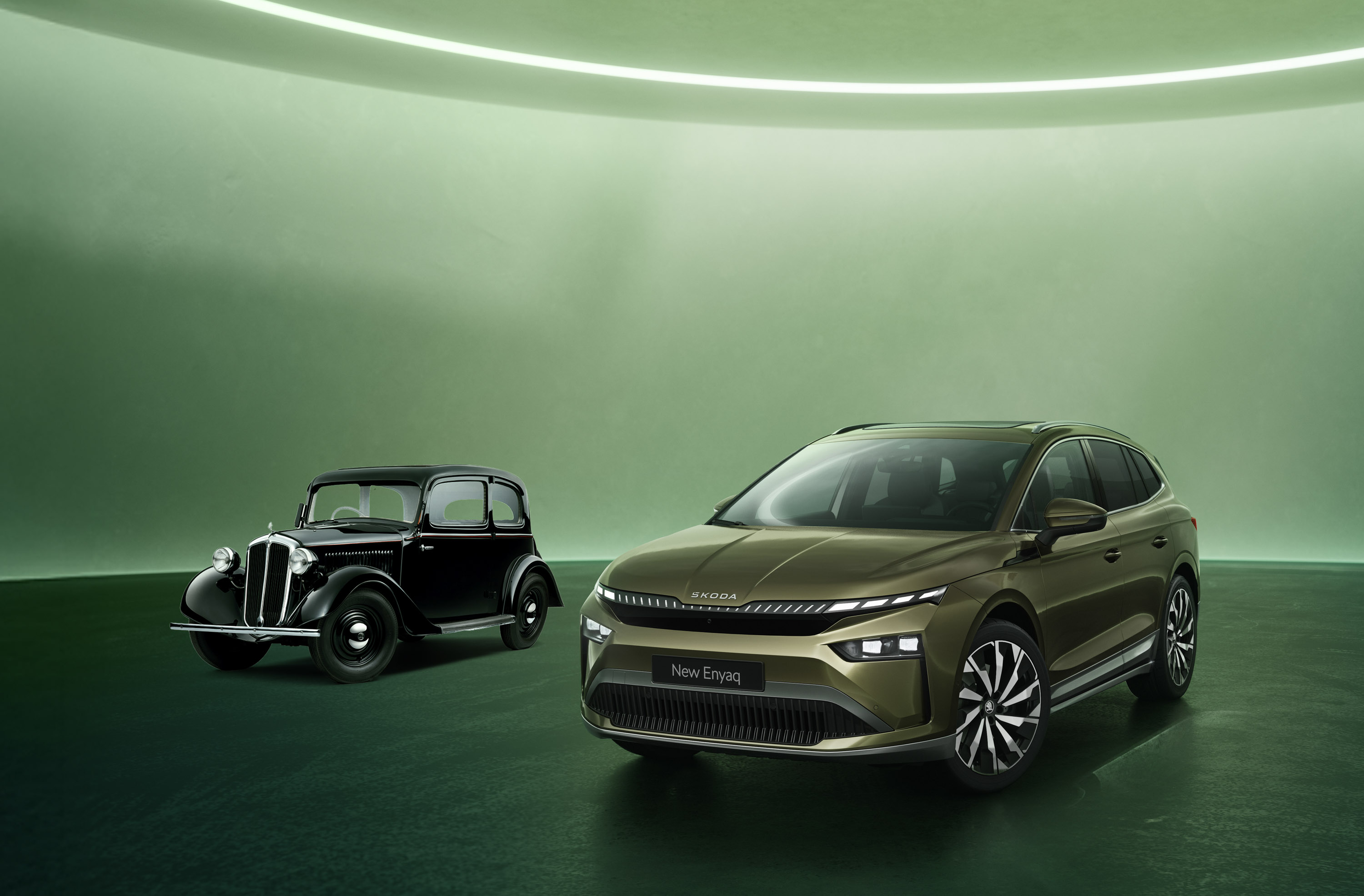 Jubiläumsbild mit dem neuen Škoda Elroq neben einem historischen Škoda Modell vor hellgrünem Hintergrund.